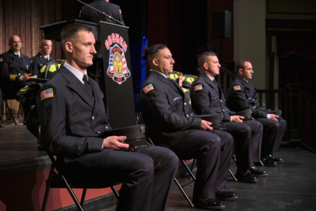 New Goshen Fire Deparment recruits, from left, Charles Hoderbaum, Brian Guerra, Jeffery Gill and Ryan Rentfrow sit on stage during their graduation ceremony at Goshen Theater on Wednesday, April 2, 2025. (Photo credit: James Korn | Eyedart)