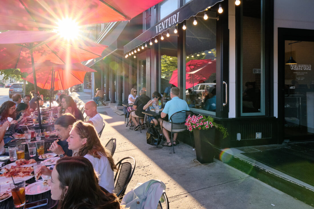 People enjoying food and drink outside in the sunshine.